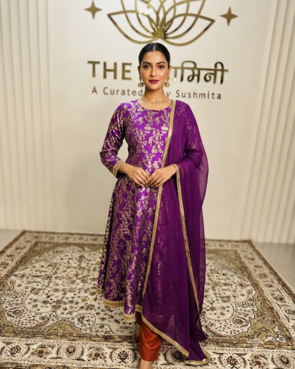 Indian model wearing a regal purple brocade Anarkali paired with vibrant orange pure silk pejami pants and a matching dupatta by The Swamini by Sushmita.