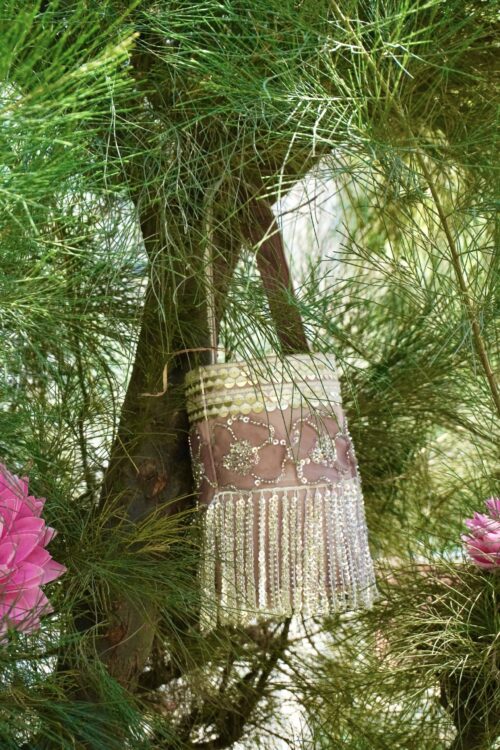 Elegant dusty pink and rose gold bucket-style bag featuring intricate floral sequin embroidery, a gold sequined top border, and dramatic shimmering fringe tassels hanging from the base.