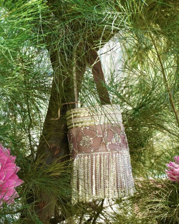 Elegant dusty pink and rose gold bucket-style bag featuring intricate floral sequin embroidery, a gold sequined top border, and dramatic shimmering fringe tassels hanging from the base.