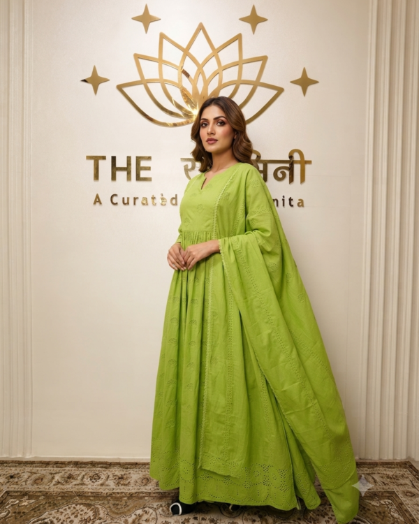 A model wearing a bright green Chikankari straight suit with matching palazzo and dupatta, posing inside a designer boutique.