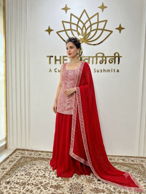 Indian model wearing a vibrant red suit set adorned with intricate Gota work, paired with a flowing flared palazzo and a matching dupatta by The Swamini by Sushmita.