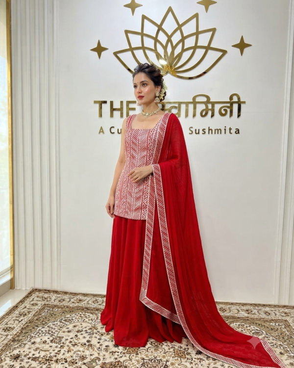 Indian model wearing a vibrant red suit set adorned with intricate Gota work, paired with a flowing flared palazzo and a matching dupatta by The Swamini by Sushmita.