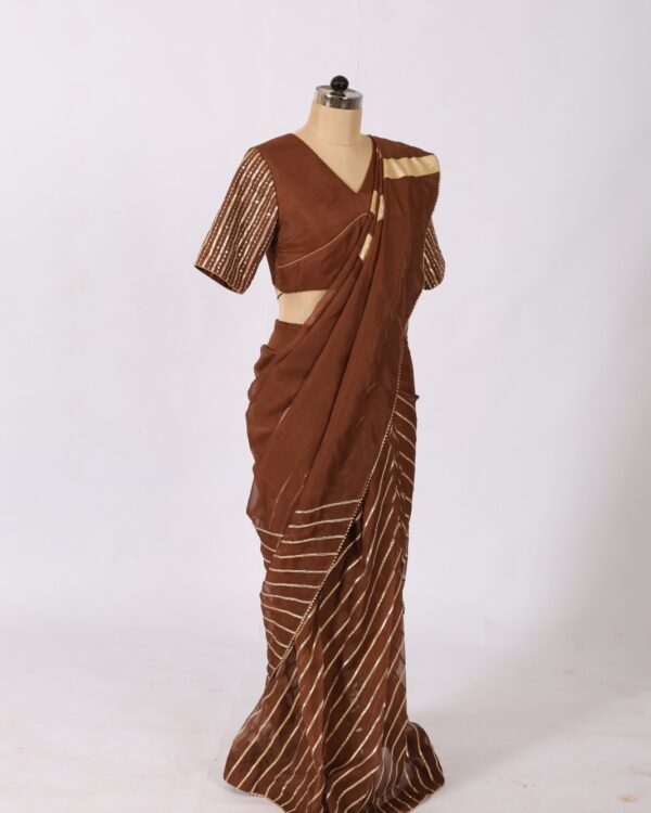 Draped brown ethnic saree showing heavy gold chevron gotta stripes across the chest and shoulder.