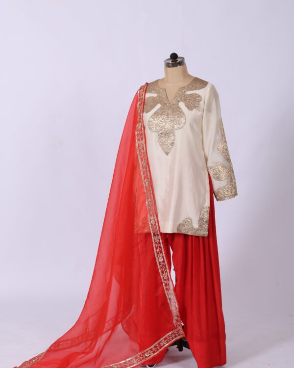 Theswamini off-white kurta featuring Gota patchwork, red crepe farshi salwar, and handwork dupatta for women's ethnic wear.